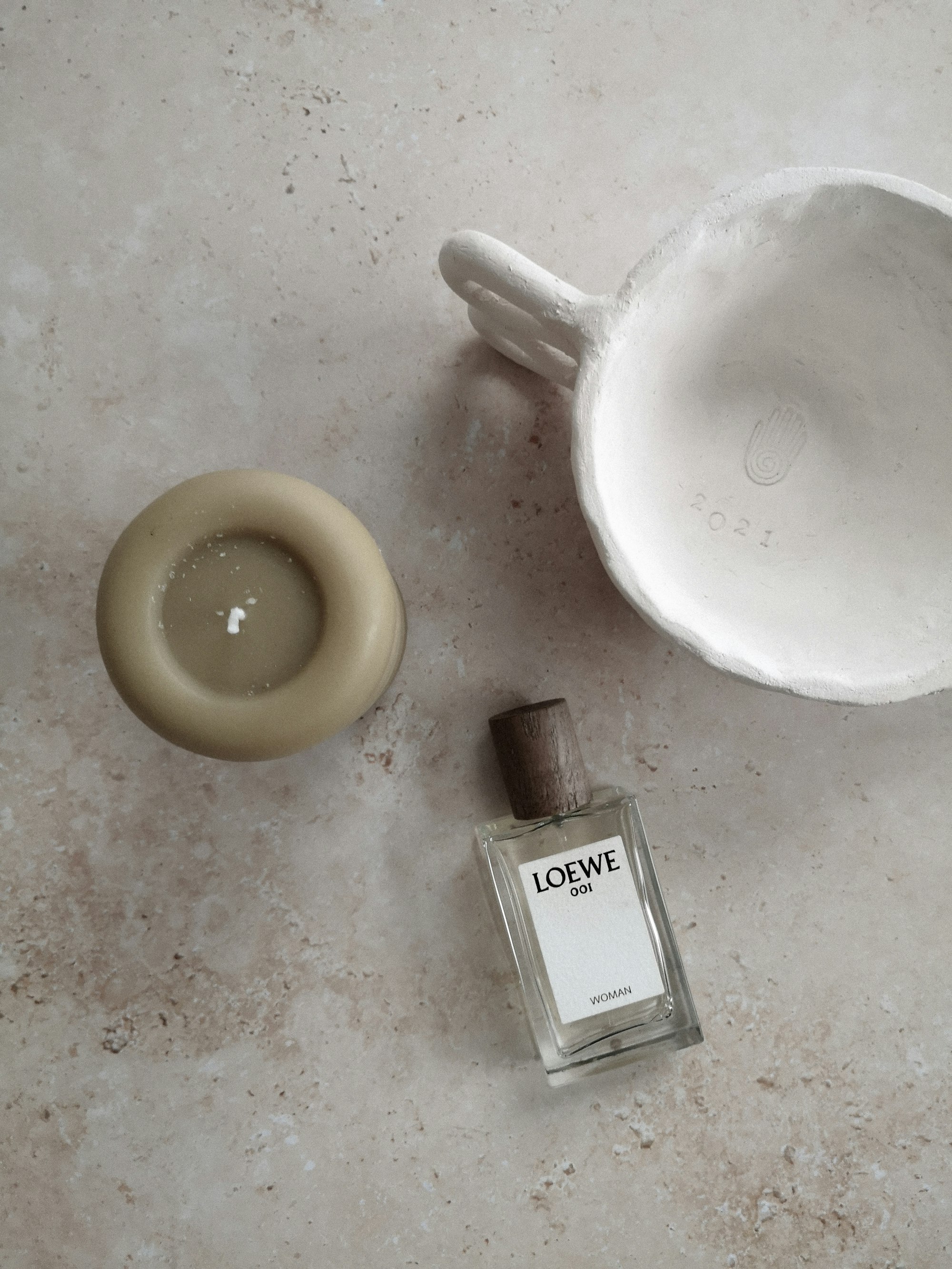 Candle, ceramics and fragrance on warm stone